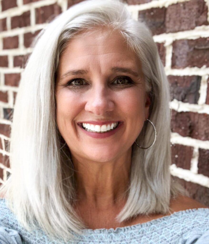 Jules Morris smiling in front of a brick wall