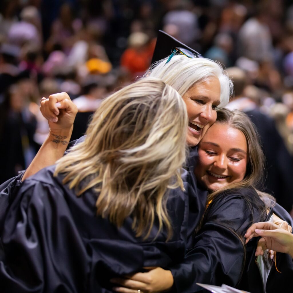 Jules sharing a joyful group hug with graduating students at commencement