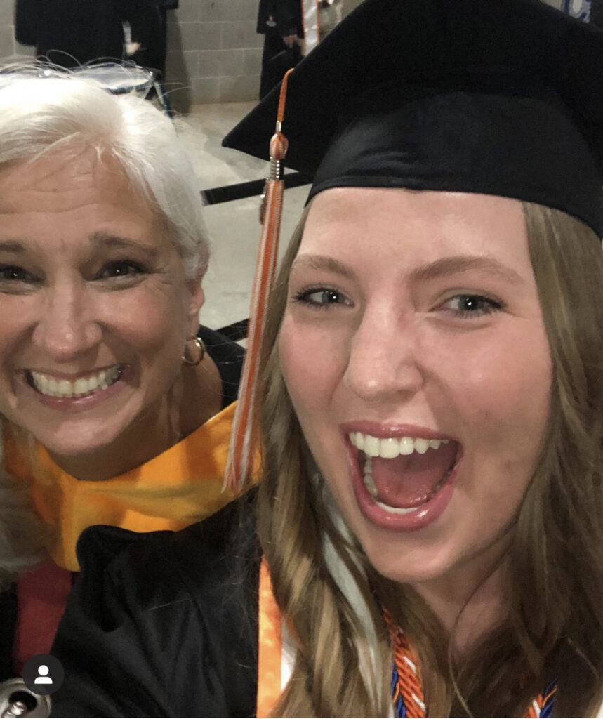 Jules and a graduate cheering in a selfie at commencement