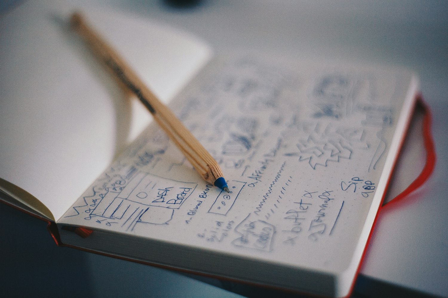 A pen resting on an open notebook with sketched ideas