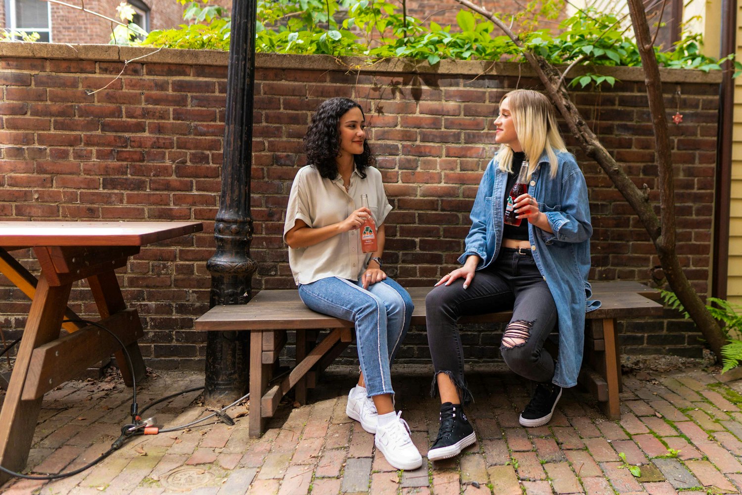 Two women talking over coffee on an outdoor bench