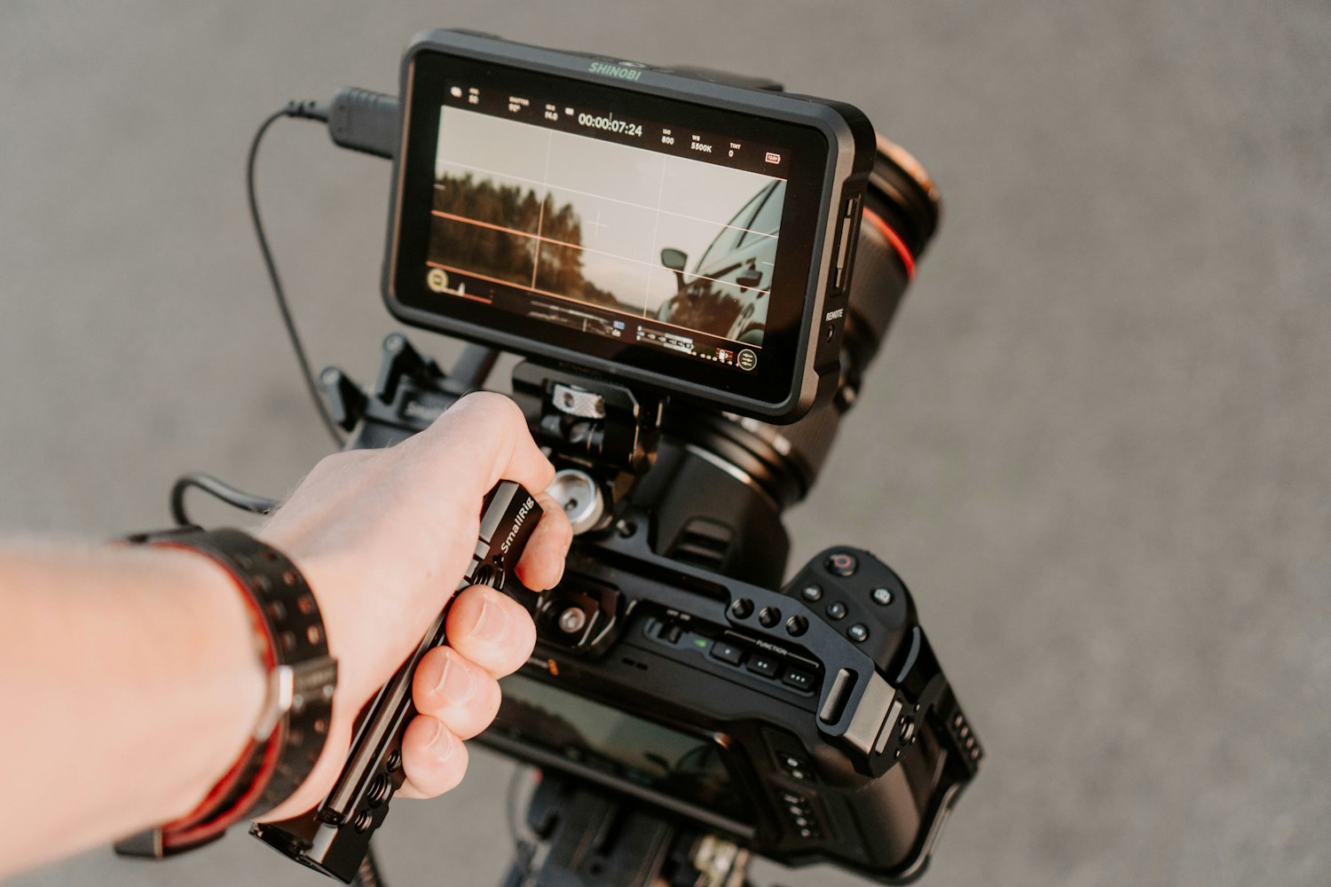 A hand holding a video camera rig while filming
