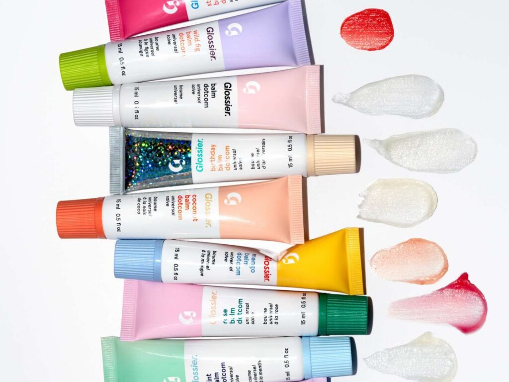 A fan of colorful Glossier tubes with product swatches