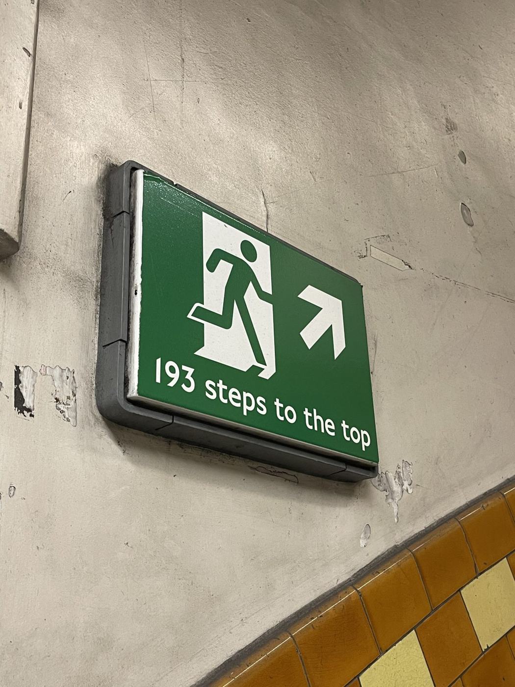 A green sign reading 193 steps to the top in a Tube station