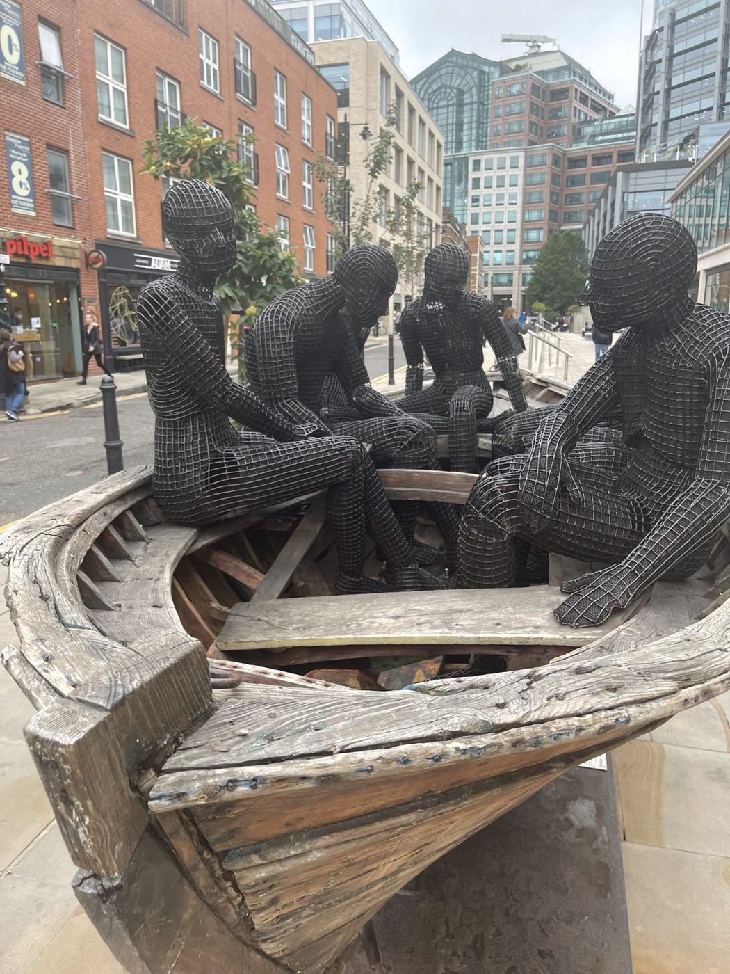 A bronze sculpture of people sitting together in a wooden boat