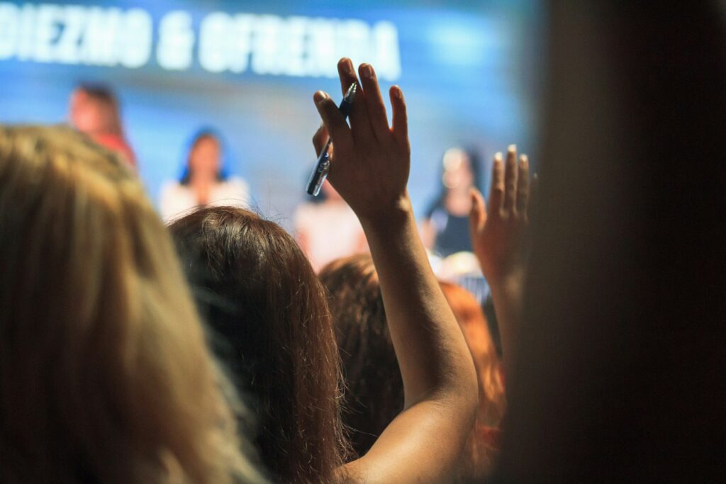 People in an audience raising their hands to ask questions