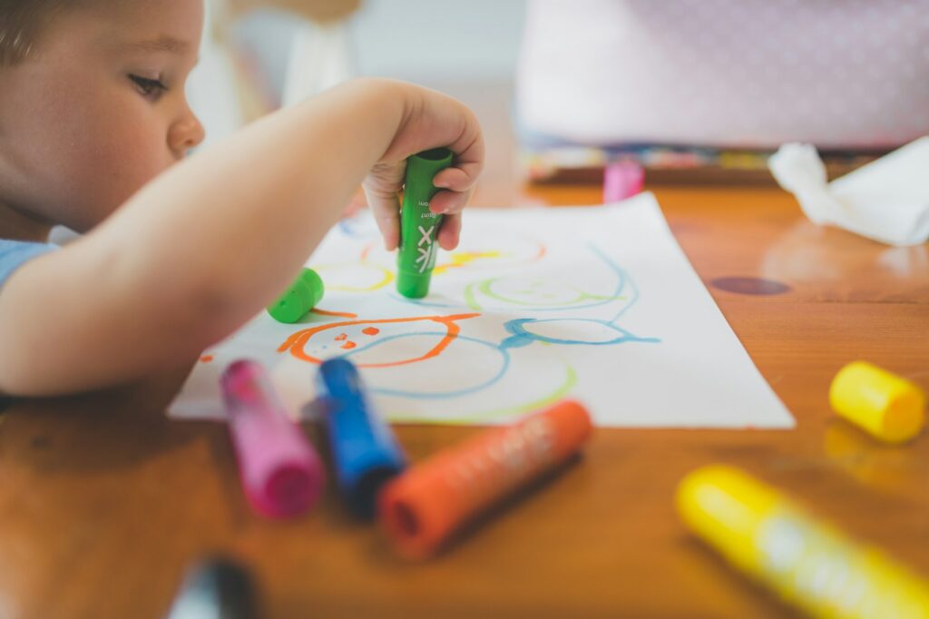 A young child drawing at a table with crayons