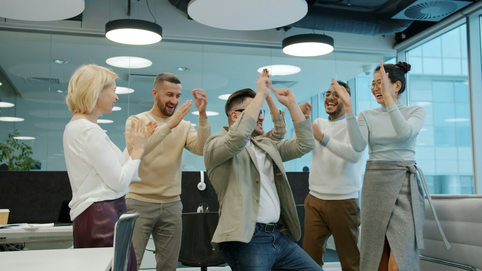 A team cheering and celebrating together in a bright office
