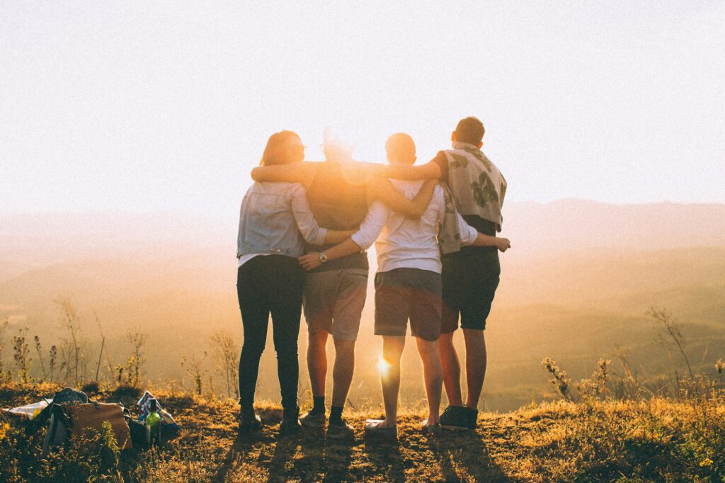 Friends with arms around each other watching the sunset