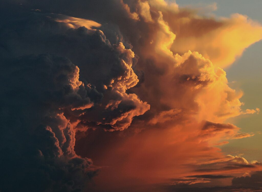 A towering storm cloud lit orange at sunset