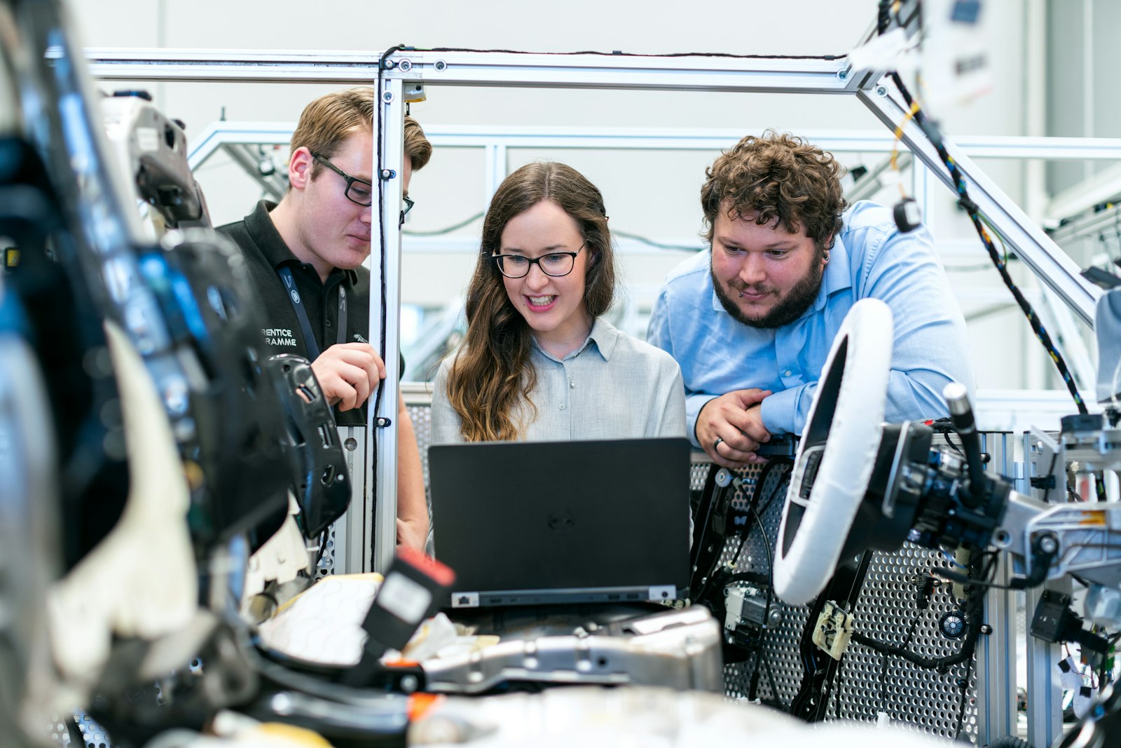 Three engineers working together around a laptop and test equipment