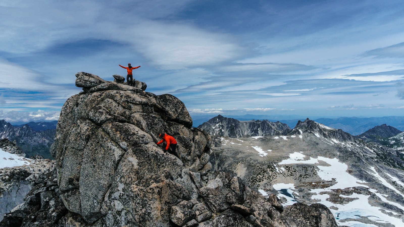 A climber standing on a rocky summit above the mountains