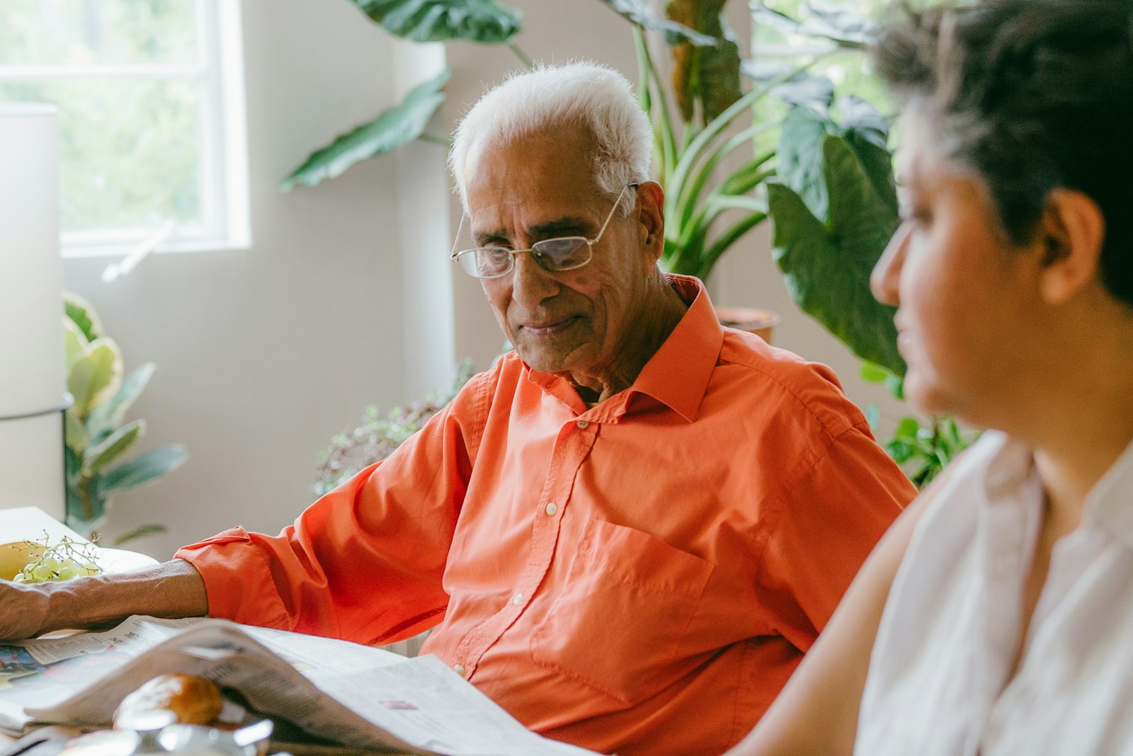 An older man smiling as he tells a story to a younger woman