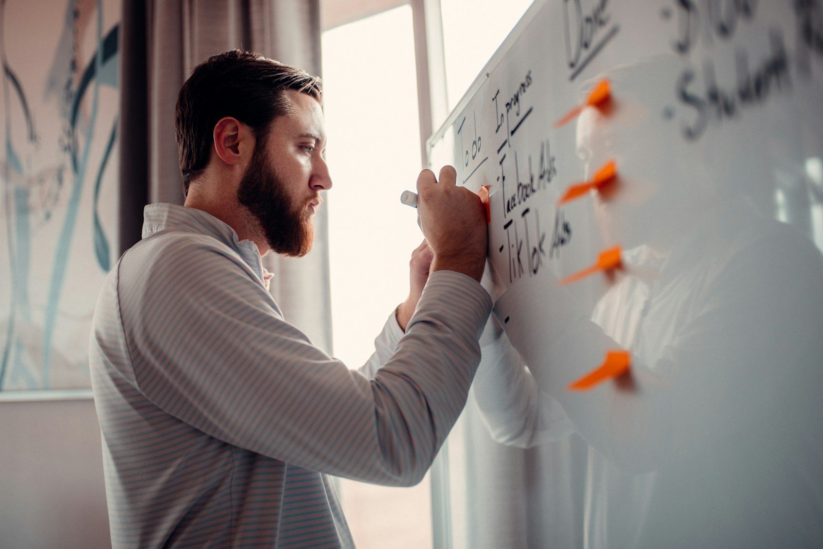 A man mapping ideas on a whiteboard covered in sticky notes