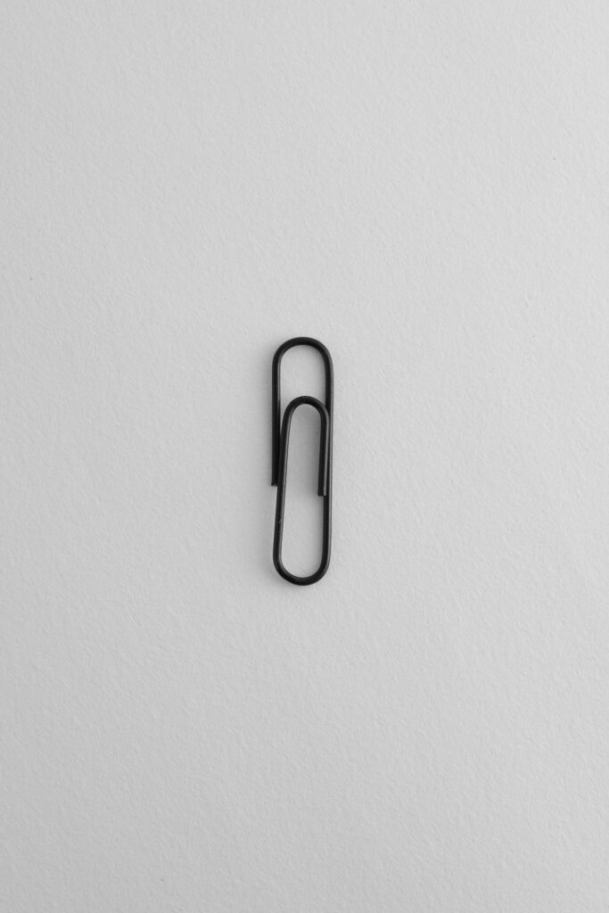 A single black paper clip on a plain white background