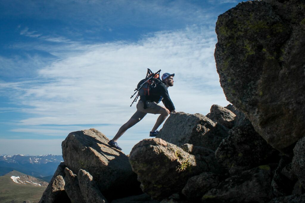 A climber scrambling up a rocky ridge high above the valley