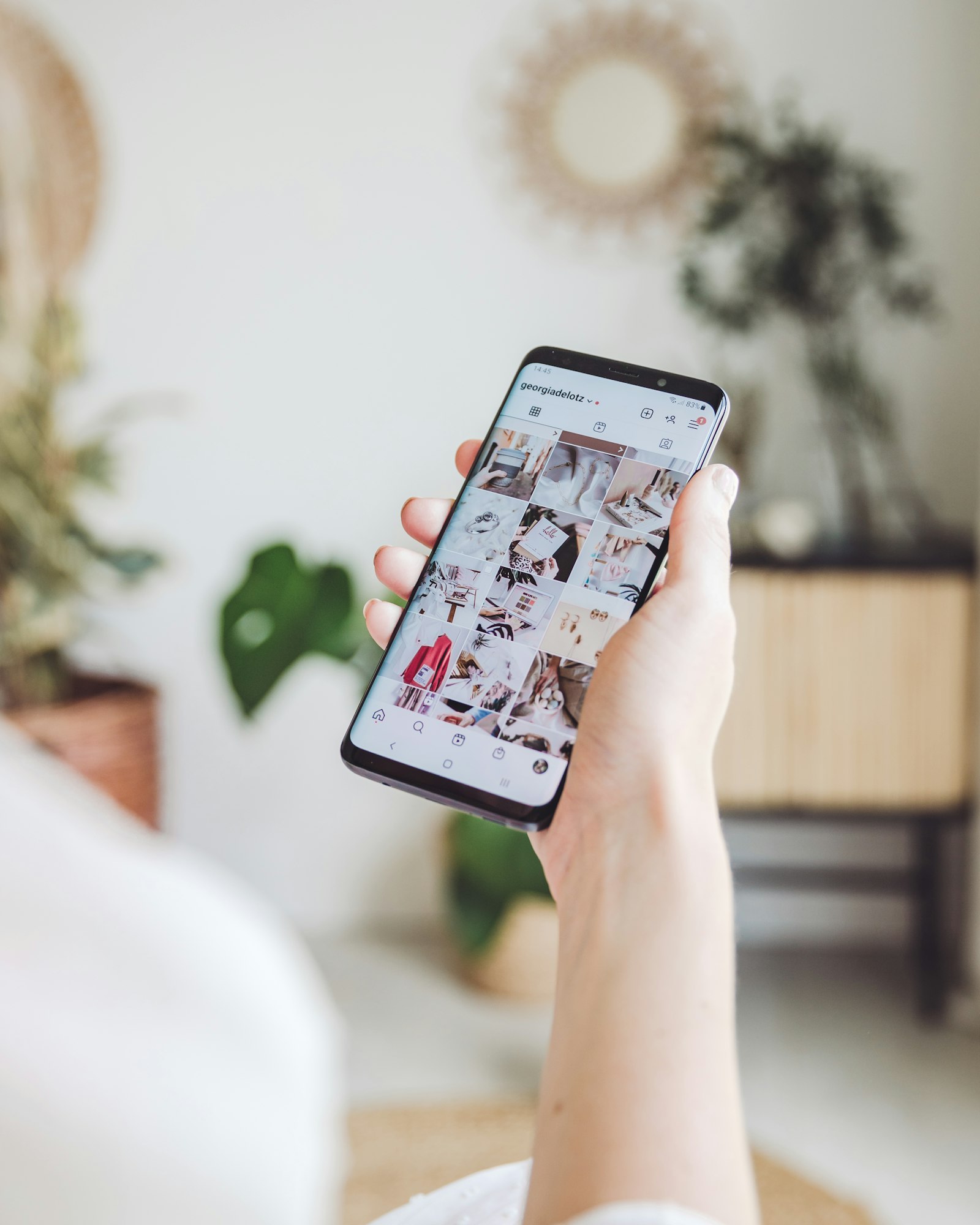 A person holding a phone and scrolling an Instagram feed