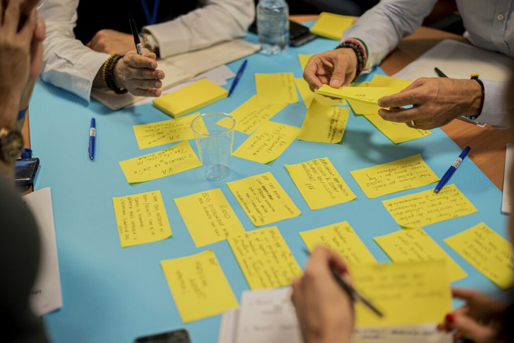 Hands placing sticky notes on a table during a co-design session