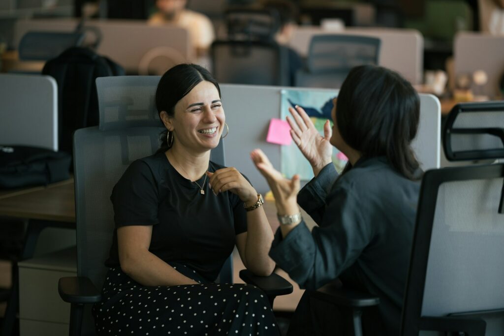 Two colleagues laughing together while talking in a modern office