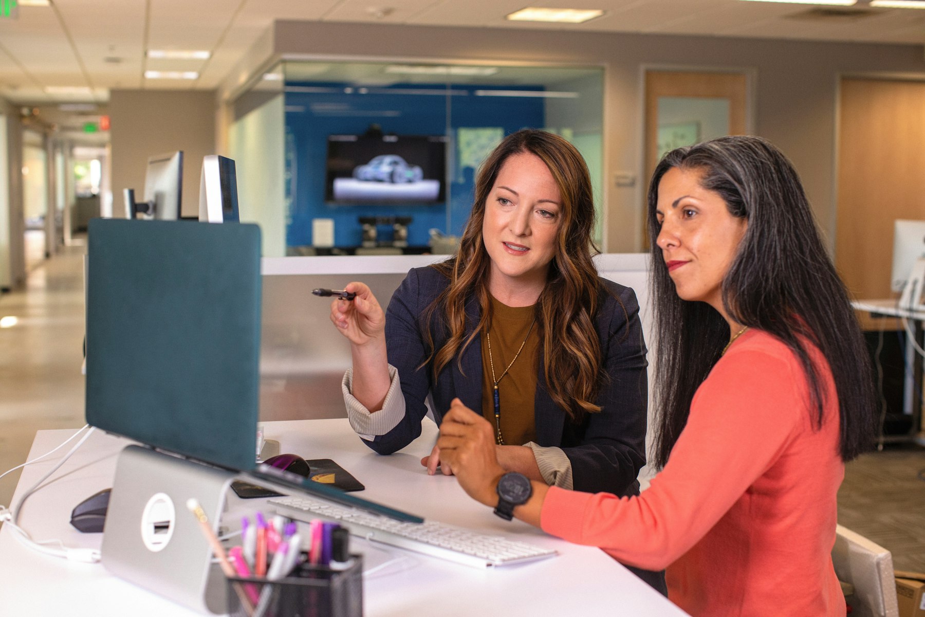 Two colleagues talking together at a table with a laptop