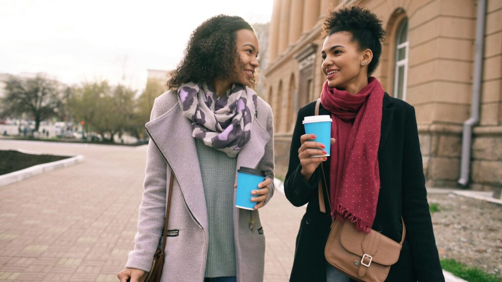 Two women walking and talking with coffee cups
