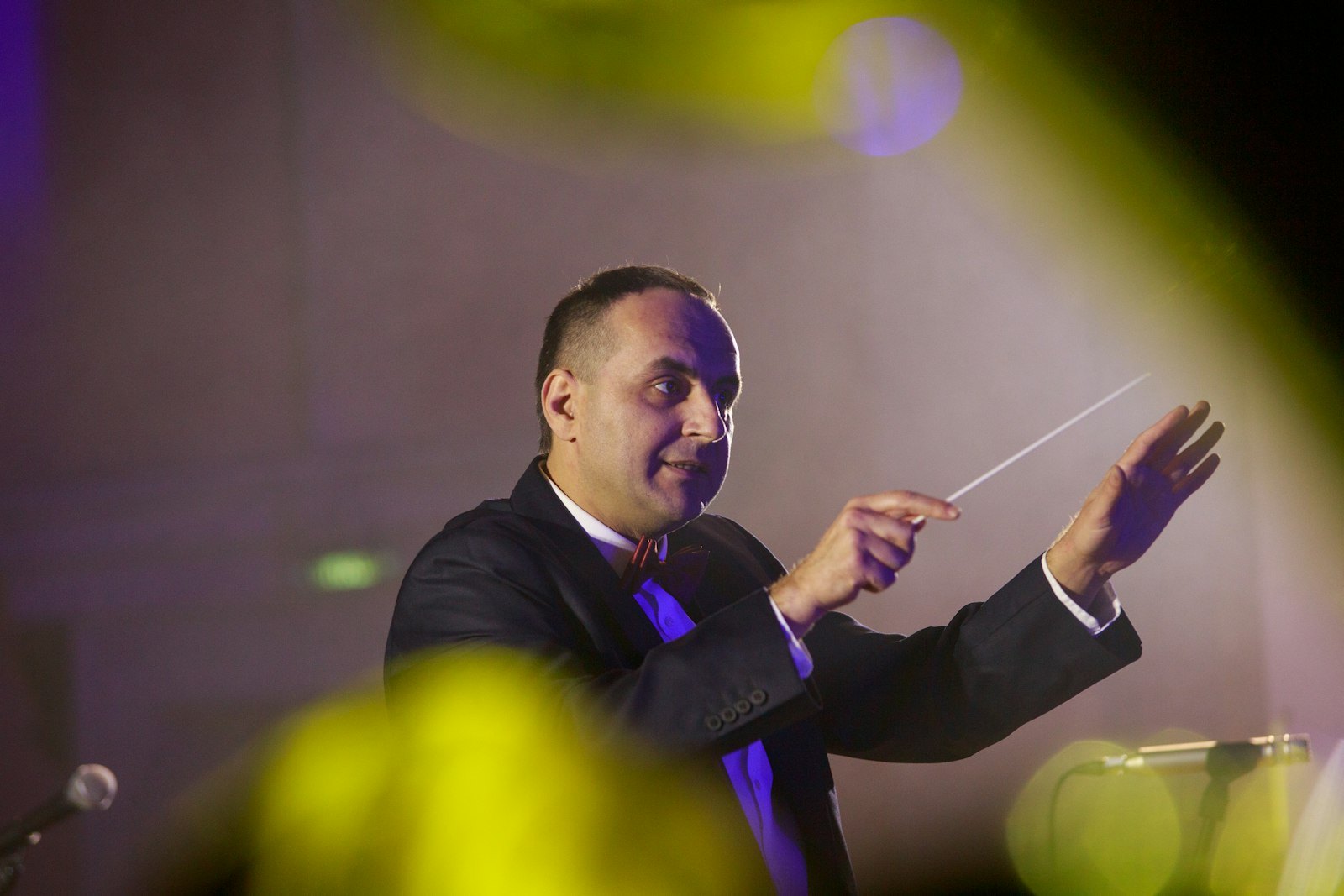 A conductor leading an orchestra with a raised baton