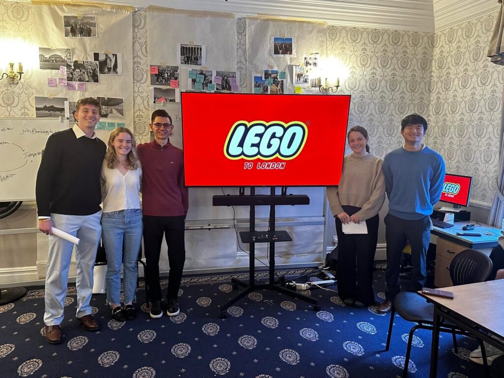 A student team presents its final concept with a LEGO slide on screen