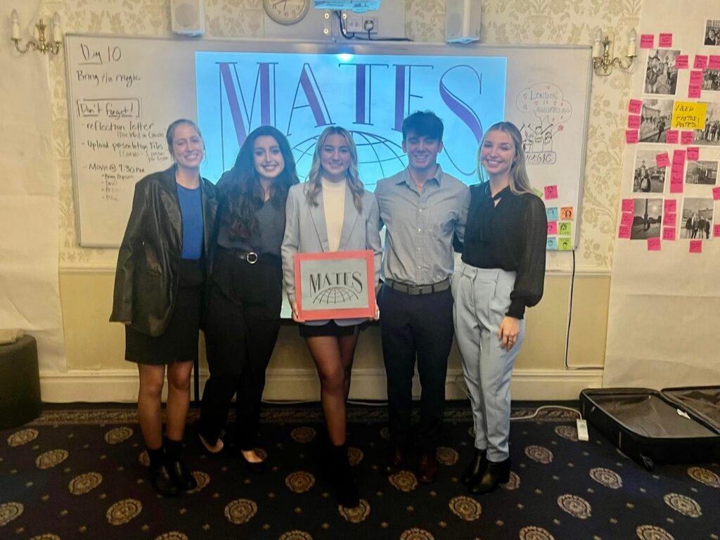 A student team holds up its MATES prototype after the final pitch