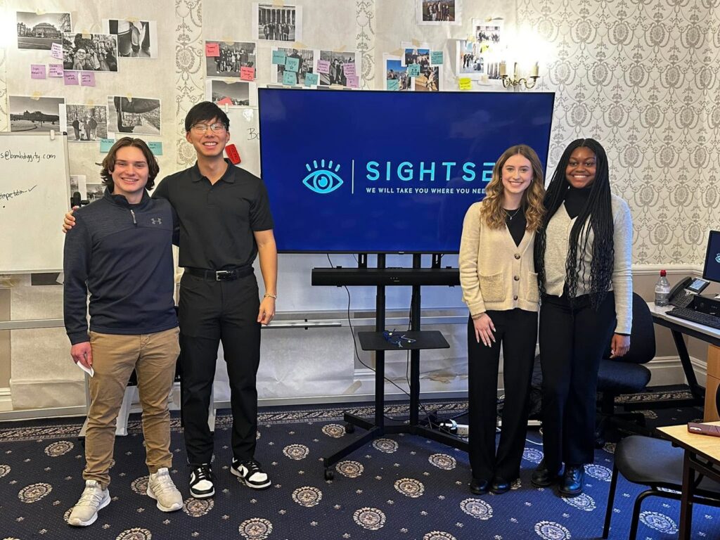 Four students stand by a screen showing their Sightsee concept