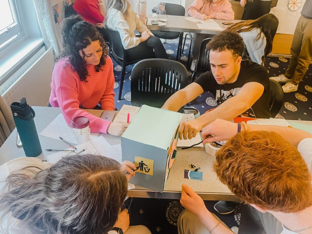 Students build a cardboard prototype together at a table