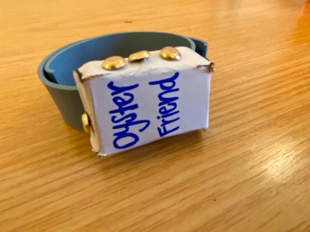 A paper prototype wristband labeled Oyster Friend