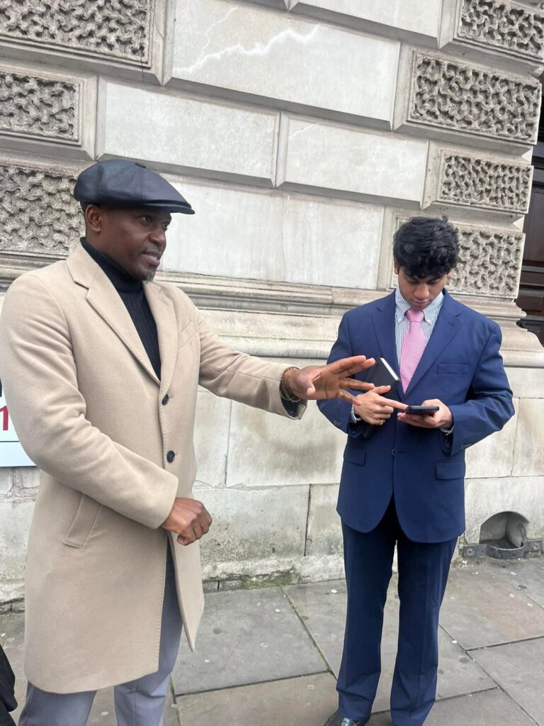 A student interviews a man in a camel coat on a London street