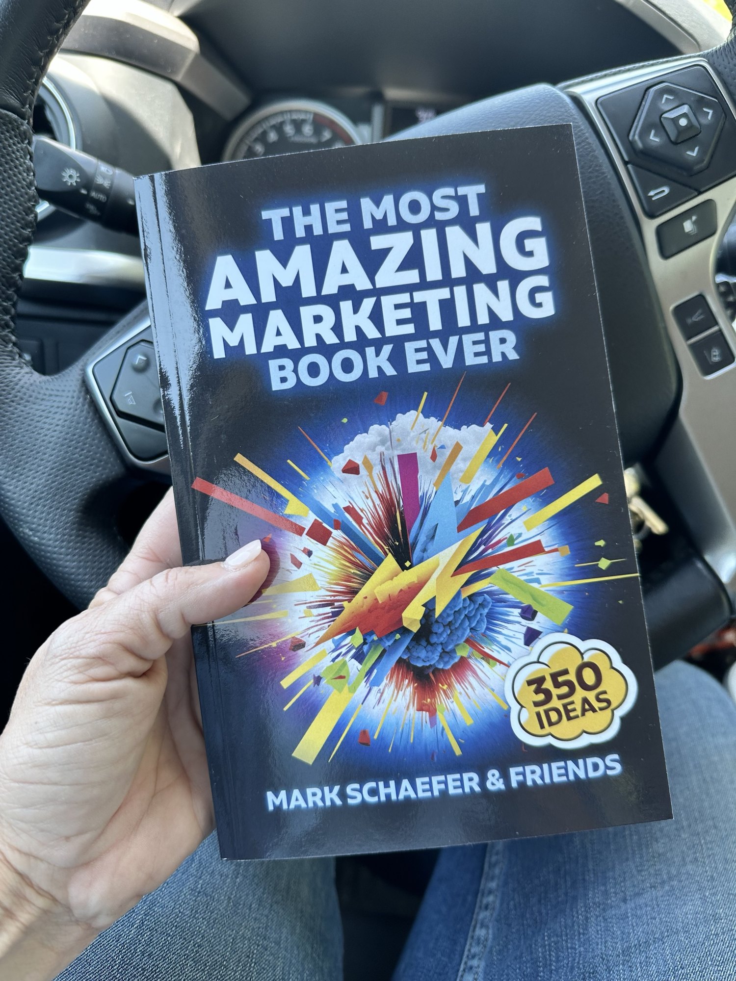 Jules holding a copy of The Most Amazing Marketing Book Ever by Mark Schaefer and Friends