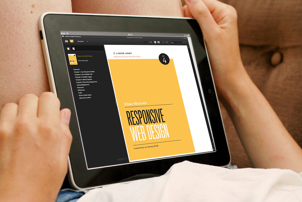 A hand holding a tablet showing a responsive web design book page