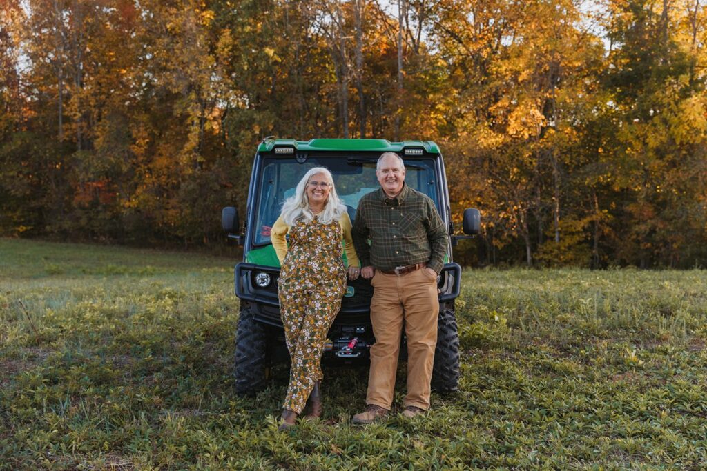 Lane and Jules Morris leaning on their John Deere XUV in a fall pasture at Sweet BombDiggity Farms