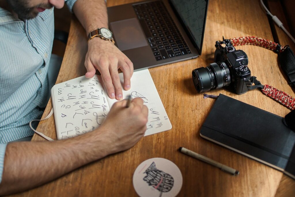 Man writing on paper in front of DSLR